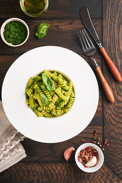 Italiaanse Fusilli Pasta met Pesto Fusilli pasta met basilicum pesto en kruiden Parmezaanse kaas basilicum en knoflook op witte plaat op oude houten tafel achtergrond Bovenaanzicht Kopieer ruimte Mock up