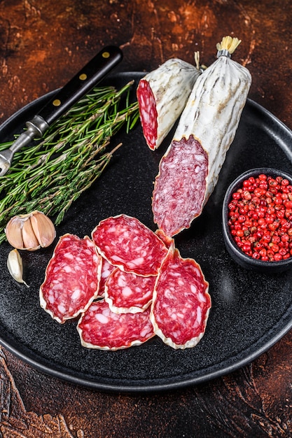 Italiaanse gesneden salami op een bord met rozemarijn en tijm.