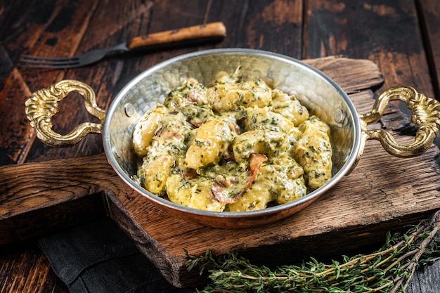 Foto italiaanse gnocchi-aardappelpasta met spinazie en parmezaanse kaas in koekenpan houten achtergrond bovenaanzicht