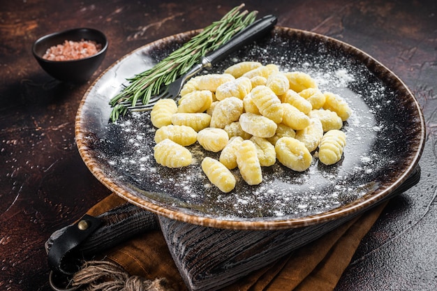 Italiaanse gnocchi dumplings Rauwe aardappel gnocchi op plaat met tijm Donkere achtergrond Bovenaanzicht