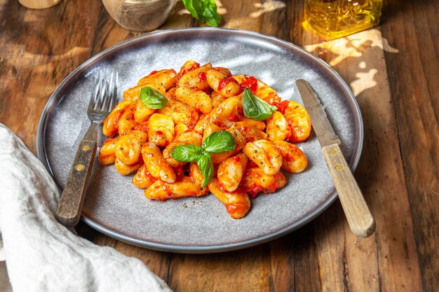 Italiaanse gnocchi met tomatensaus en basilicum op houten achtergrond