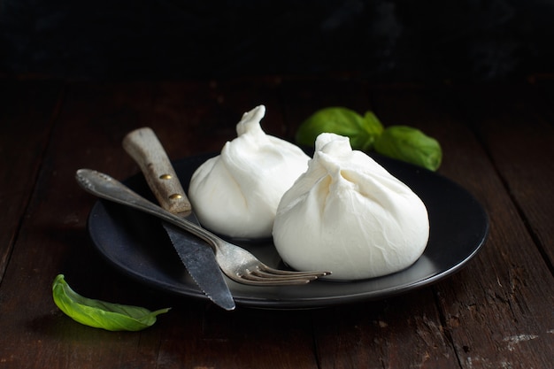 Italiaanse kaasburrata met vork en mes op een donkere ondergrond