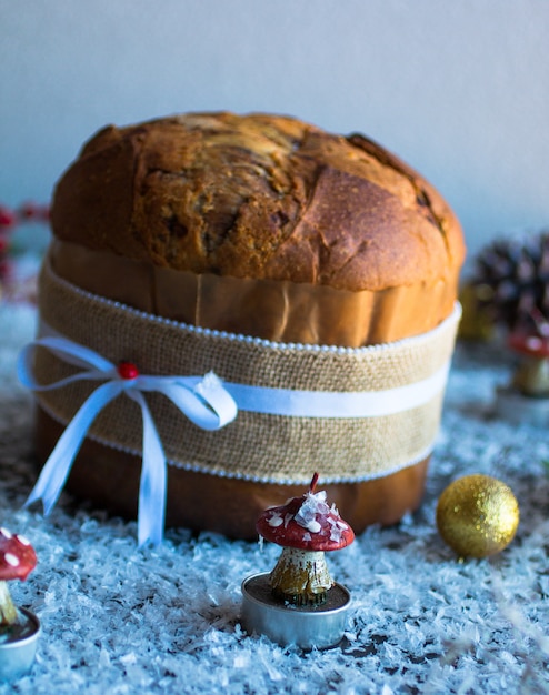 Italiaanse Kerstmiscake van chocoladepanettone met de kaarsenpine kegels van snuisterijdecoratie op een houten achtergrond.