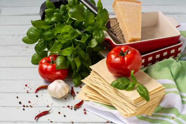 Italiaanse keuken-lasagne. producten voor lasagne tomaten, basilicum, deeg, ovenschaal.