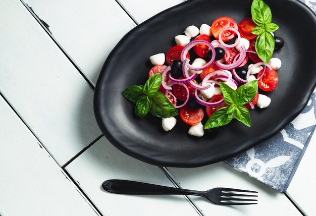 Foto italiaanse keuken verse italiaanse caprese salade met mozzarella en tomaten op een donker bord