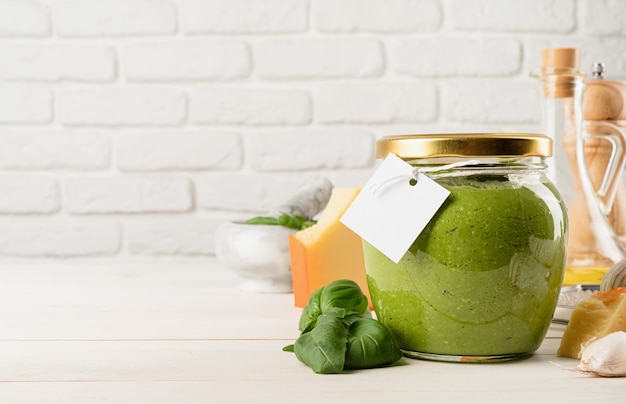 Italiaanse keuken. Voorbereiding van zelfgemaakte Italiaanse pestosaus. Zelfgemaakte pesto-saus in een glazen pot met een blanco tag, mock-upontwerp