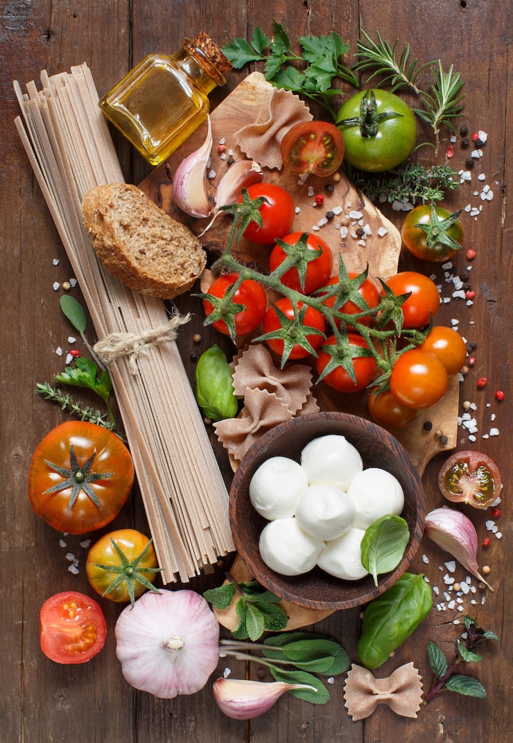 Foto italiaanse kookingrediënten mozzarella, pasta, tomaten, knoflook, kruiden, olijfolie en andere