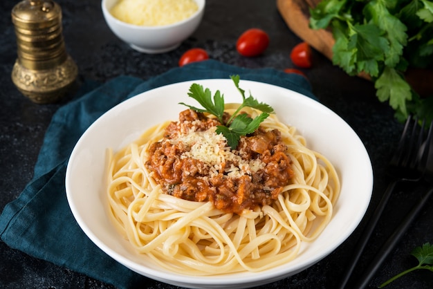 Italiaanse pasta bolognese met greens op een zwarte achtergrond, close-up