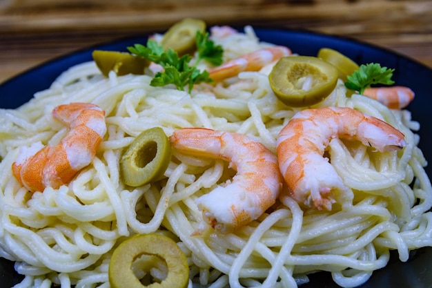 Italiaanse pasta met garnalen en olijven in een zwart bord