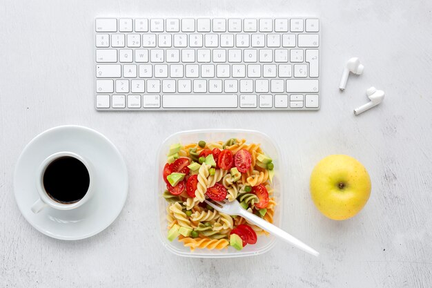 Italiaanse pasta met groenten op kantoor met toetsenbord