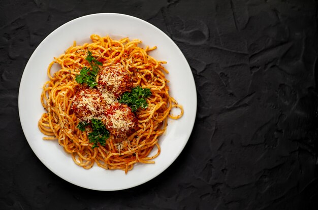 Italiaanse pasta met tomatensaus en gehaktballen in een plaat met kruiden op steen