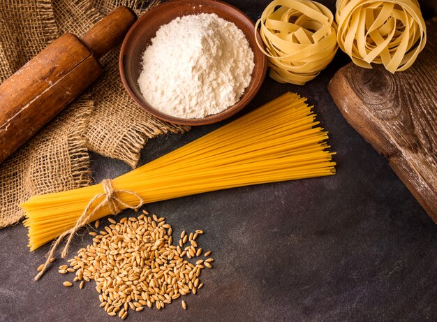 Italiaanse pasta, spaghetti, fettuccine, tarwe, deegrol, bloem op een gestructureerde achtergrond.