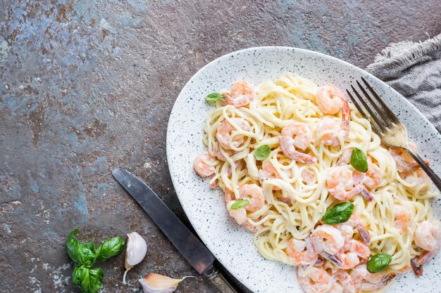 Italiaanse pasta spaghetti in een romige saus met garnalen in een bord, bovenaanzicht