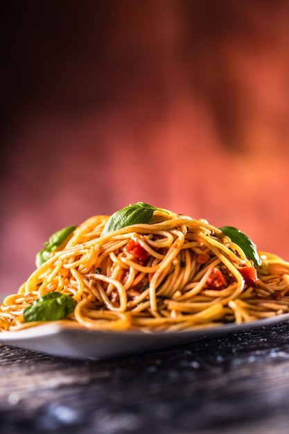 Italiaanse pasta spaghetti met tomatensaus basilicum en parmezaanse kaas in witte plaat.