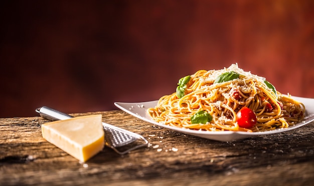 Italiaanse pasta spaghetti met tomatensaus basilicum en Parmezaanse kaas in witte plaat.