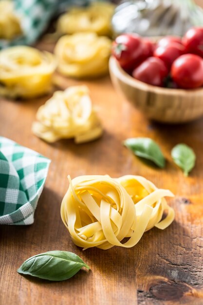 Italiaanse pasta tagliatelle op tafel met basilicum en tomaten.