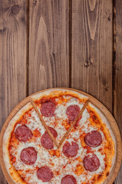 Italiaanse Pepperoni-pizza met salami op donkere houten hoogste mening als achtergrond. Italiaanse traditionele gerechten. Populair straatvoedsel