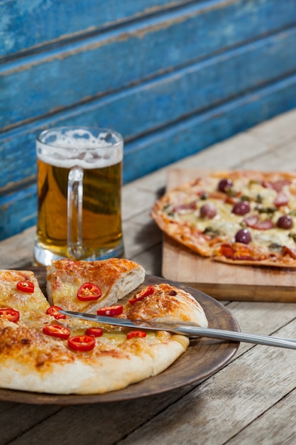 Italiaanse pizza geserveerd met glas bier op houten plank