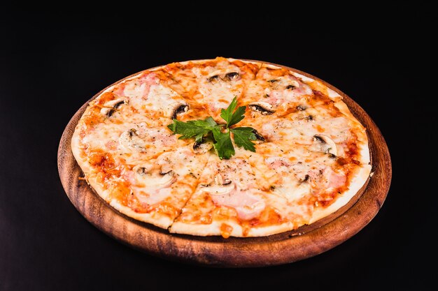 Italiaanse pizza met champignons op een houten bord op een zwarte achtergrond