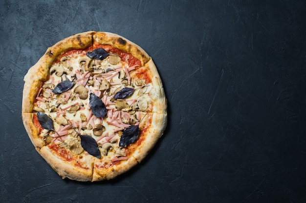 Italiaanse pizza met ham, champignons en basilicum.