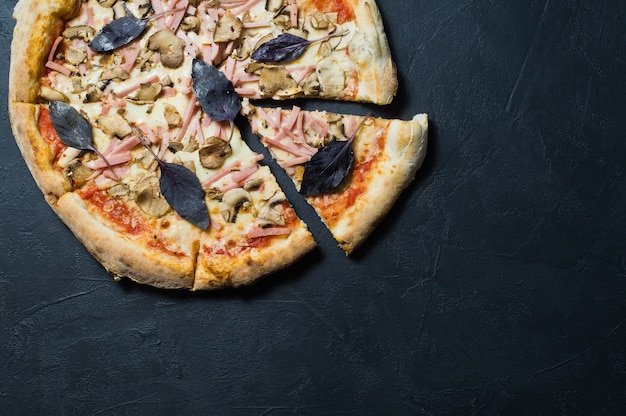 Italiaanse pizza met ham, champignons en basilicum.