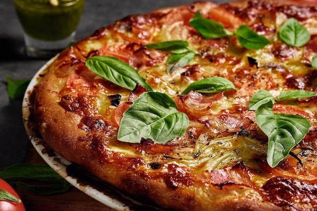 Italiaanse pizza met ham, mozzarella, tomaten en basilicumbladeren op een donkere achtergrond Close-up met selectieve focus op zelfgemaakte pizza