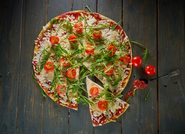 Italiaanse pizza met tomaten, kaas en kruiden op vintage houten tafel. bovenaanzicht