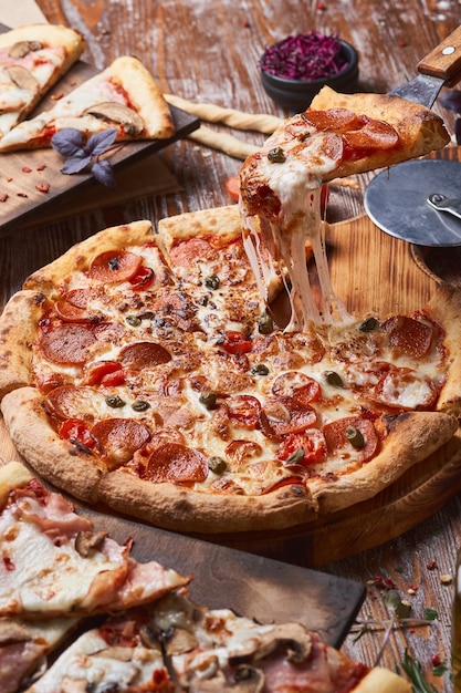 Foto italiaanse pizza op een houten tafel. een stuk hete pizza met kaas die zich uitstrekt.