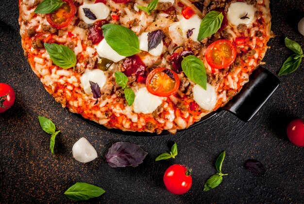 Italiaanse pizza op grill bord met verschillende ingrediënten op donkere achtergrond