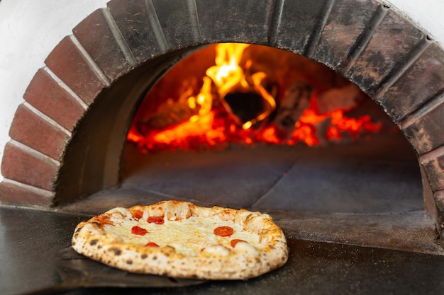 Italiaanse pizza wordt gebakken in een houtoven. De kok legt de pizza op een schep in de oven