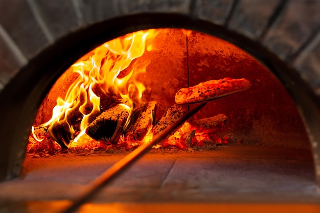 Italiaanse pizza wordt gebakken in een houtoven. De kok legt de pizza op een schep in de oven