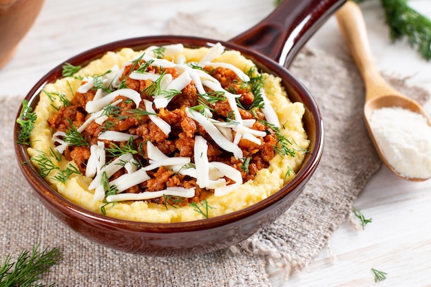 Italiaanse polenta met ragu bolognese op een witte houten tafel