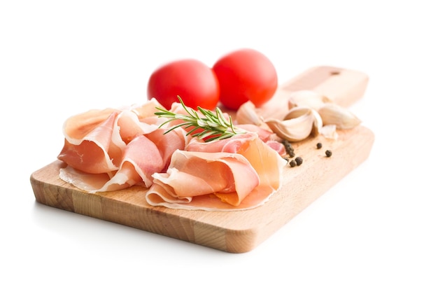 Italiaanse prosciutto crudo of jamon met pepertomaten, knoflook en rozemarijn op snijplank