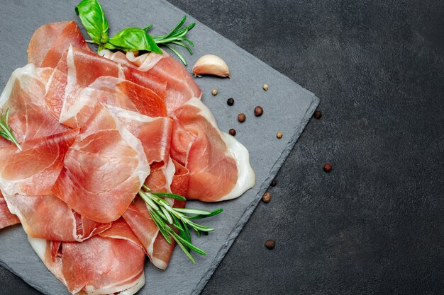 Italiaanse prosciutto crudo of Spaanse ham. Rauwe ham op stenen snijplank