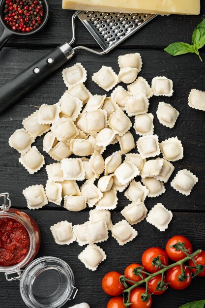 Italiaanse Ravioli-ingrediënten met verse ricottabladeren en tomaten op een zwarte houten tafel als achtergrond bovenaanzicht plat lag