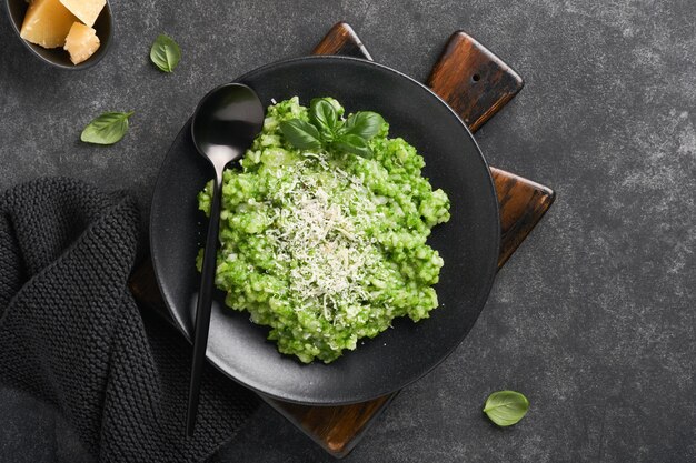 Italiaanse risotto Heerlijke risotto met pestosaus of daslook pesto basilicum Parmezaanse kaas en glas witte wijn op donkere leisteen tafel achtergrond Italiaans diner Bovenaanzicht met kopie ruimte