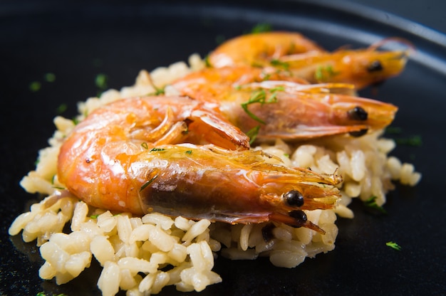 Italiaanse risotto met garnalen op een zwarte plaat.