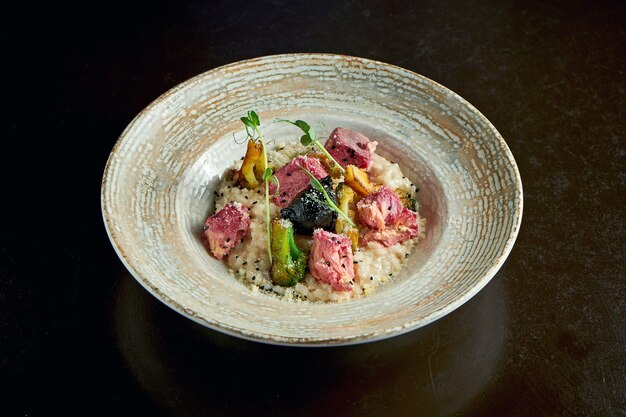 Italiaanse risotto met gebakken zalm en broccoli in een plaat op een zwarte achtergrond