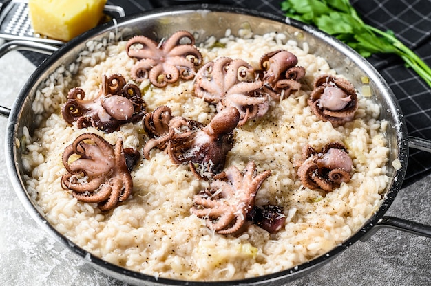 Italiaanse Risotto met octopus en champignons versierd met Parmezaanse kaas en peterselie. Bovenaanzicht