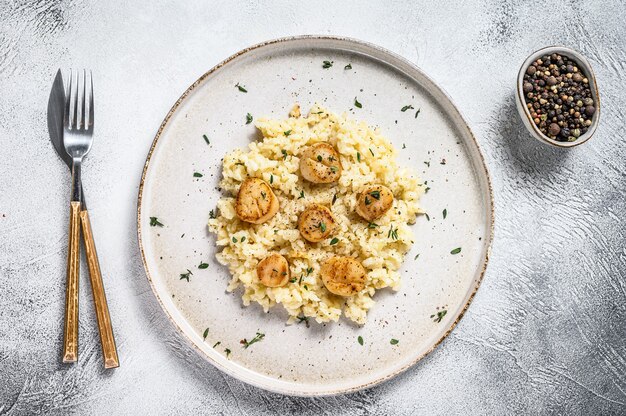 Italiaanse Risotto met pan aangebraden overzeese sint-jakobsschelpen op wit. Bovenaanzicht.