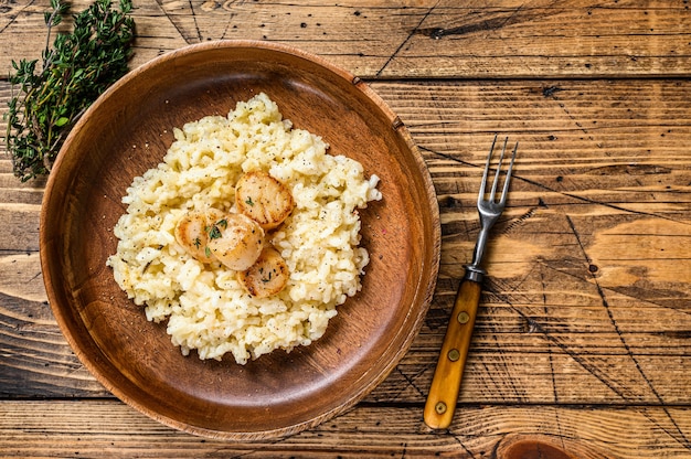 Italiaanse Risotto met Sint-jakobsschelpen in een pan. houten achtergrond. Bovenaanzicht. Ruimte kopiëren.