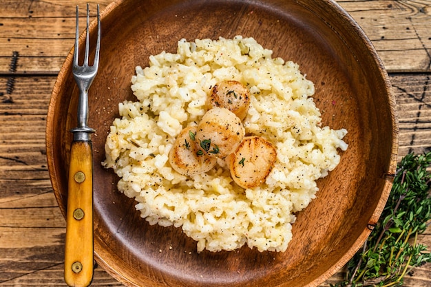 Italiaanse Risotto met Sint-jakobsschelpen in een pan. houten achtergrond. Bovenaanzicht.