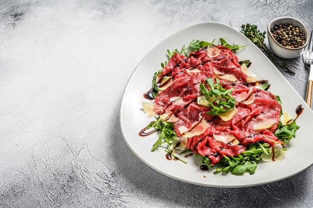 Italiaanse rundercarpaccio met rucola salade en Parmezaanse kaas op grijze tafel