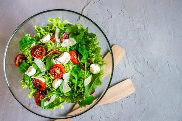 Italiaanse salade met sla en rucola in glazen kom op betonnen ondergrond met kopieerruimte