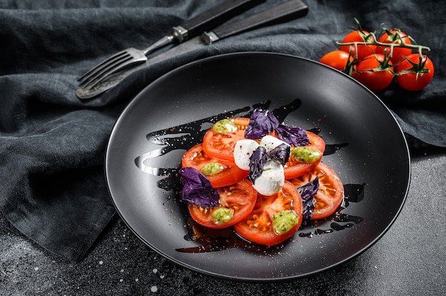 Italiaanse traditionele caprese salade. Cherrytomaatjes, mozzarellakaas, basilicum, pestosaus