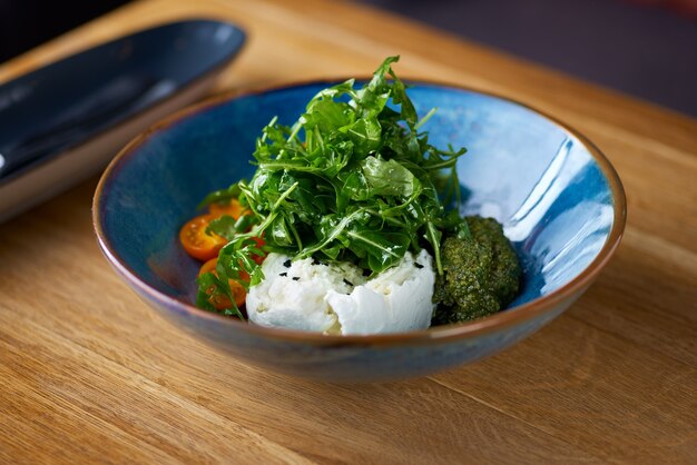 Italiaanse verse kaas burrata met kleurrijke cherrytomaatensalade, rucola en basilicum met pestosaus