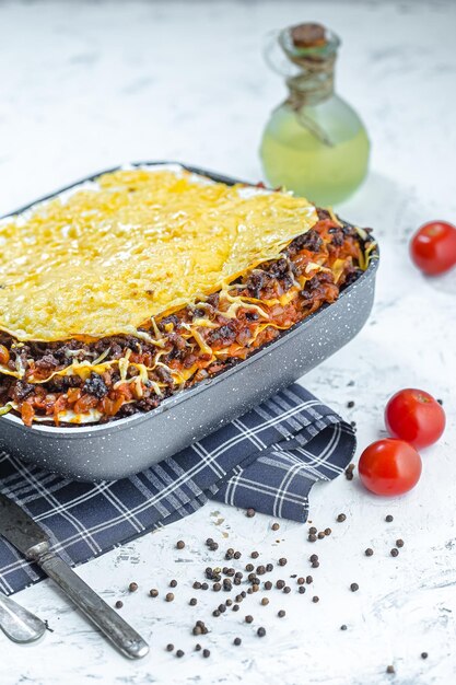 italiaanse zwarte lasagne in een diepe rechthoekige aarden pot of bord of schaal of pan, op een wit marmer