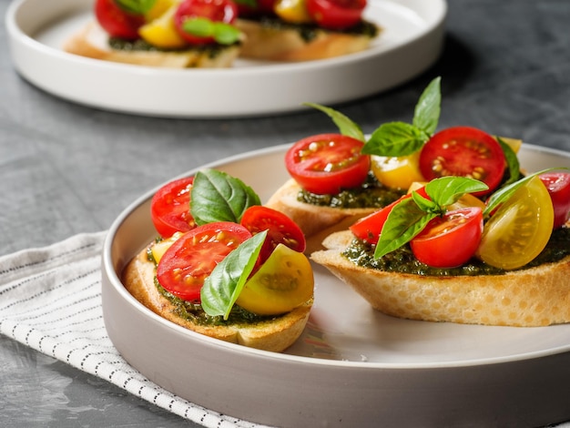 Bruschetta di antipasti italiani con basilico di pomodoro e pesto su un tavolo grigio spazio di copia