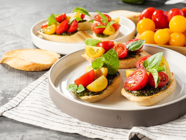 Bruschetta di antipasti italiani con basilico di pomodoro e pesto su un tavolo grigio spazio di copia