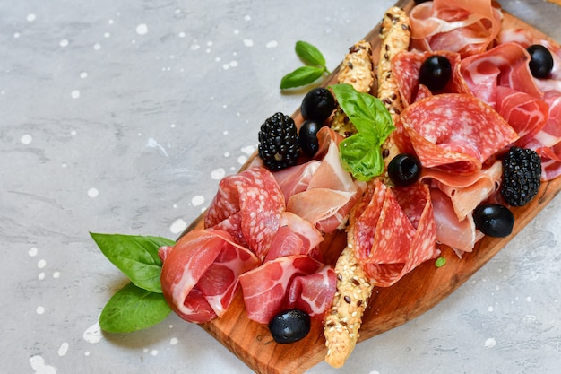 italian antipasti prosciutto, salami, bresaola olives tomatoes and grissini bread sticks. aperitif happy hour